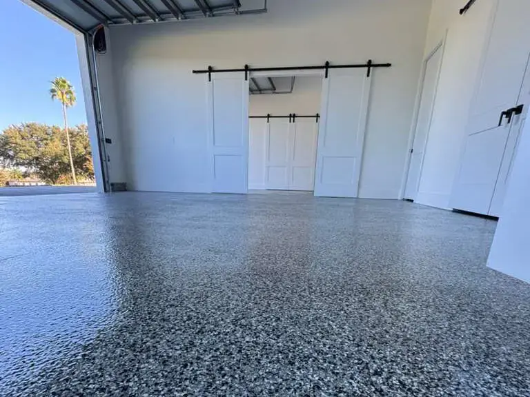 Clean, polished epoxy garage floor in a bright, open Tampa garage with white walls and sliding barn doors
