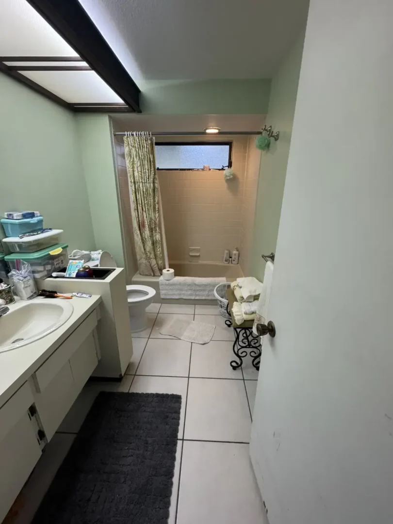 Let's Transform Your Bathroom Together Small bathroom with a tiled floor, sink vanity, toilet, and bathtub with a patterned shower curtain
