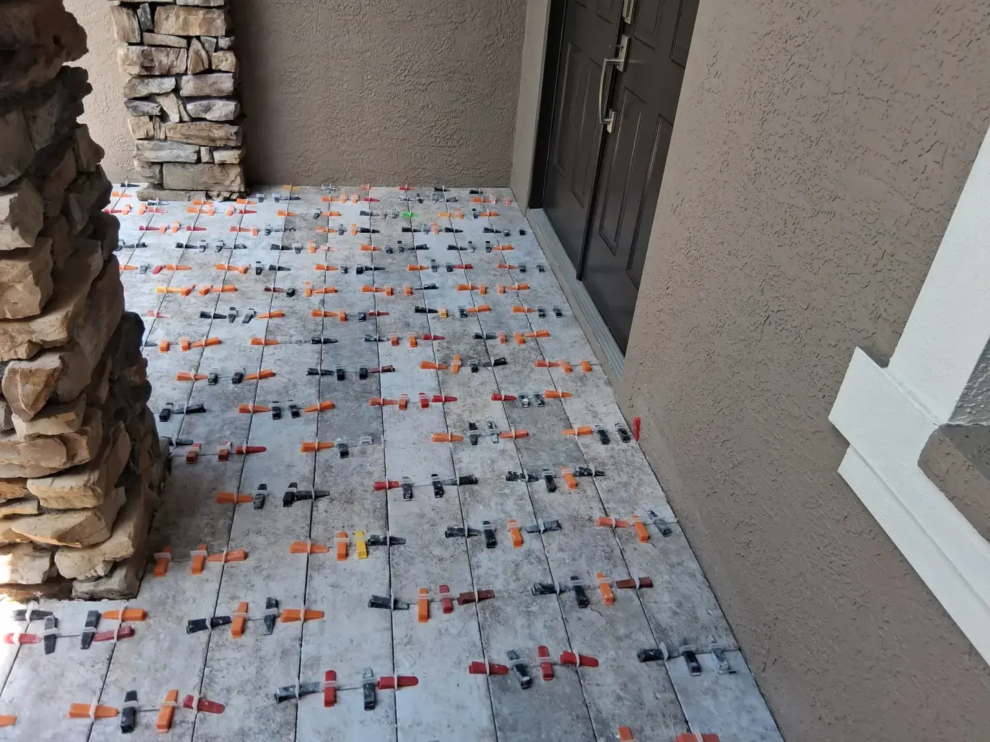 How Did Our Tile Floor Installation Transform This Front Entry in Odessa, FL? Porcelain tile floor installed on a residential front entryway in Odessa, FL with stone columns