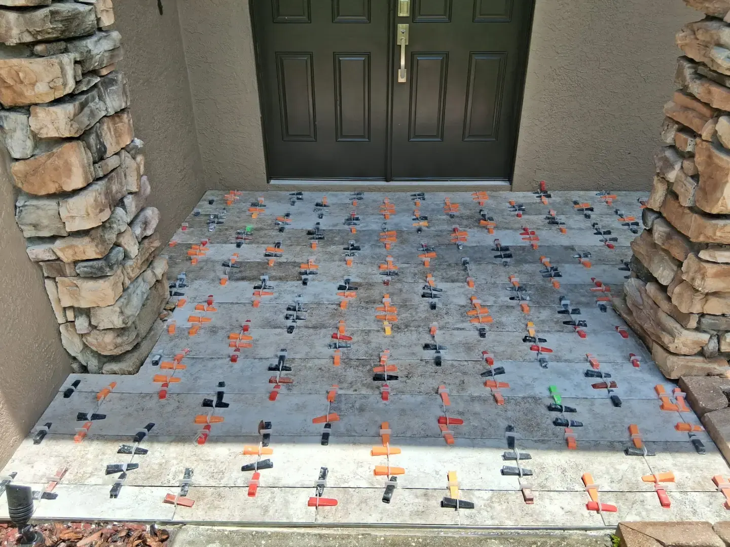 How Did Our Tile Floor Installation Transform This Front Entry in Odessa, FL? Porcelain tile floor installed on a residential front entryway in Odessa, FL with stone columns