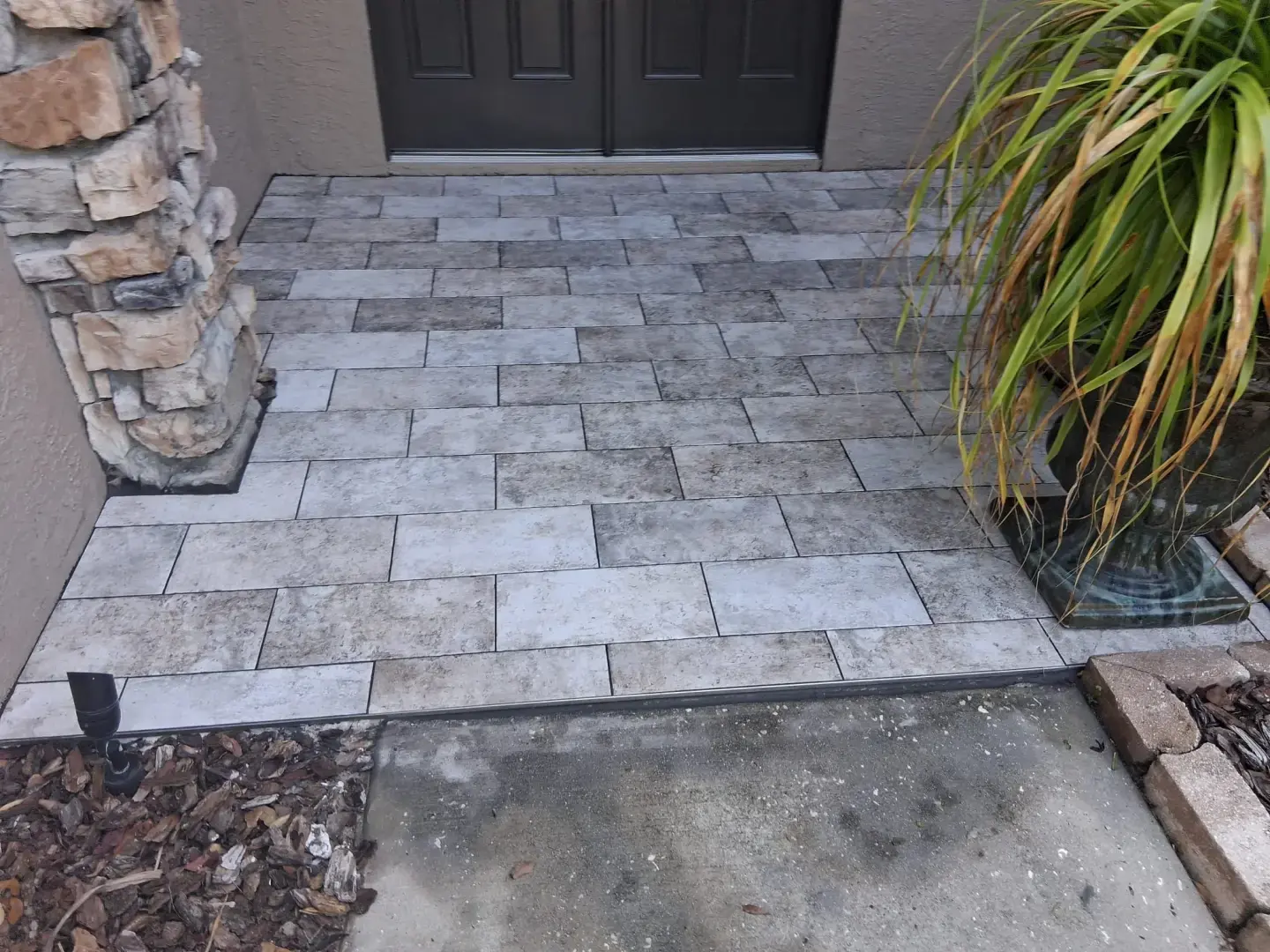 How Did Our Tile Floor Installation Transform This Front Entry in Odessa, FL? Porcelain tile floor installed on a residential front entryway in Odessa, FL with stone columns
